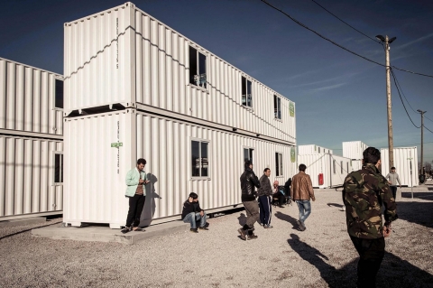 Migrants walk past housing containers in the refugee camp in the port town of Calais, in northern France, on Feb. 16, 2016. 