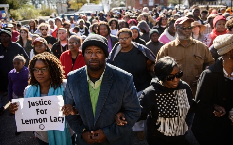 Shaune Walters, left to right, Shawn Elliott Richardson and Cassandra Ottley link arms following a march to honor the memory of Lennon Lacy on Dec. 13, 2014, in Bladenboro, N.C
