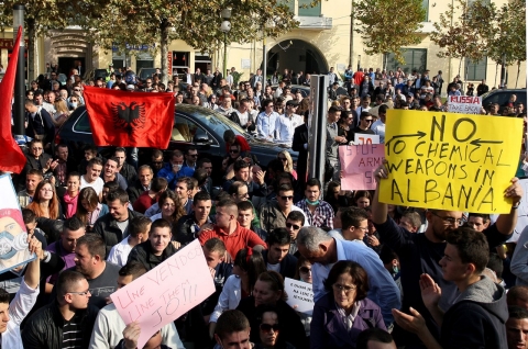 Albanian environmental activists hold up national flags and signs as they take part in a protest in front of the Albanian parliament in Tirana on Nov. 14, 2013.