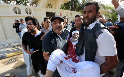 People assist a man who was injured Nov. 15, 2013 after Libyan militiamen opened fire on a crowd wanting them to move out of their headquarters in southern Tripoli