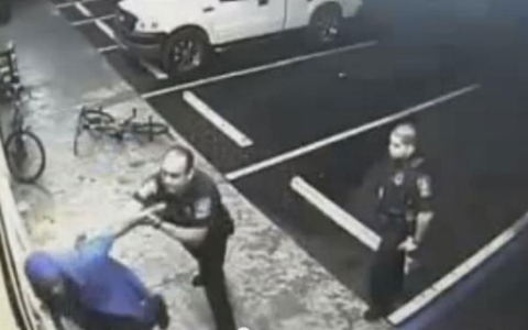 Police officers stopping and searching a customer in a still from the store's video footage.