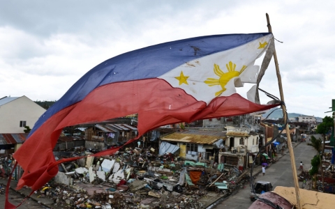 A tattered Philippines flag flies over debris left by Typhoon Haiyan.