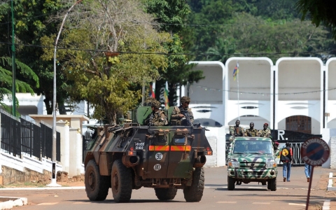 French soldiers in an armored vehicle pass ex-Seleka rebels in truck as they patrol in front of the presidential palace in Bangui on Dec. 8, 2013