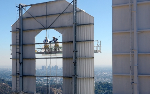 Workers clean the Hollywood sign in front of the backdrop of downtown Los Angeles.