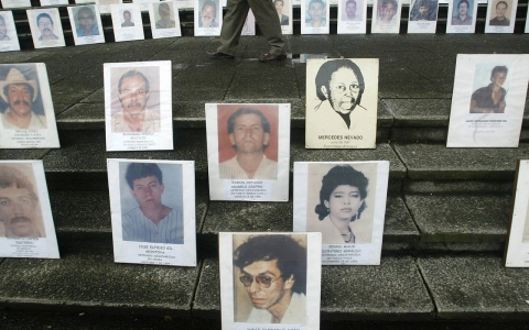 A pedestrian walks amid portraits of people disappeared during the armed conflict in Colombia.