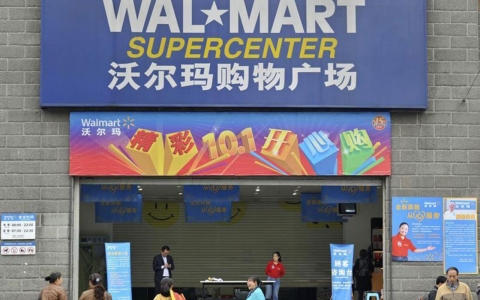 Employees stand in front of the entrance to a Walmart Supercenter in Chongqing, China on Oct. 24, 2011.