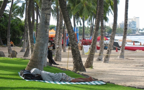 A man sleeps near a surf board rental stand at Waikiki Beach in Honolulu.