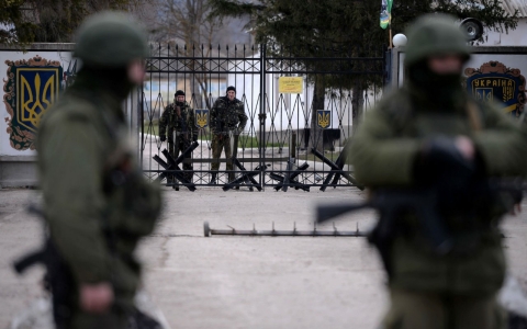 Armed men, believed to be Russian servicemen, stand guard outside an Ukrainian military base in Perevalnoye Thursday.
