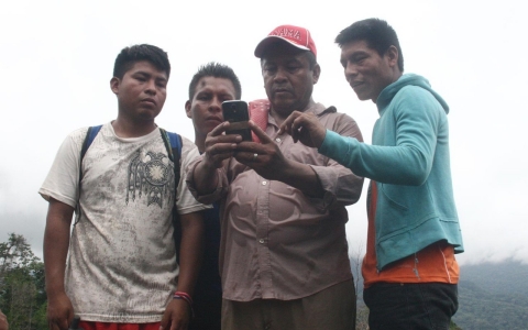 Carlos Gomez, red hat, coordinator for the Rainforest foundation, and three of the workshop participants, entering a GPS point with a cell phone.