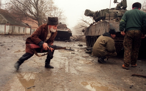 A Chechen volunteer (L) takes cover behind a Russian tank during a street fighting in Grozny opposing Russian troops on Jan. 1, 1995.