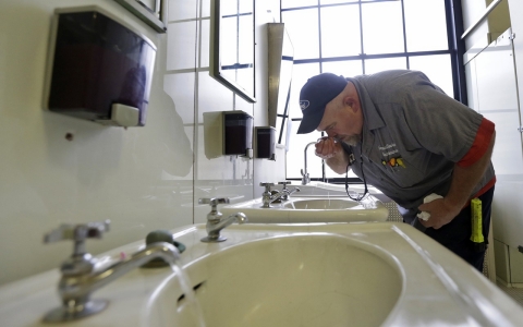 Al Jones of the West Virginia state government's General Services Division tests the water as he flushes the faucet Monday at the State Capitol in Charleston, W.Va.