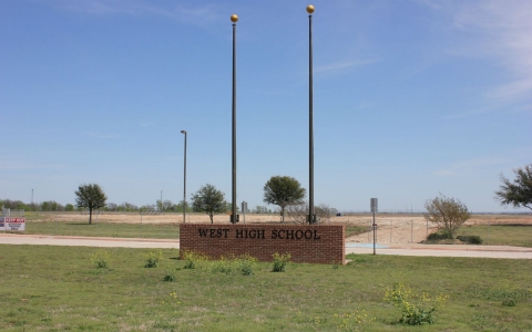 Only the brick sign and flagpoles remain of West High School, which was one of many buildings and homes destroyed last year.