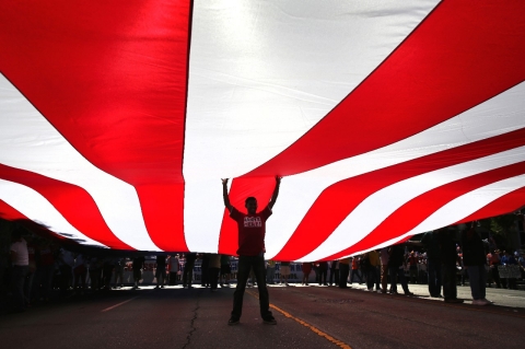 Immigration advocates support an American flag while taking part in a National Day of Dignity and Respect march on October 5, 2013 in Los Angeles, California.
